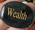 Pietra ovale nera lucida con incisione dorata Wealth tenuta in mano - Agata Indiana