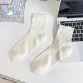 Calze beige minimaliste in cotone pettinato con trama a coste verticali su un tavolo - Alla caviglia / crema