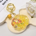 Detail of seashell oil-filled keychain with yellow resin, glitters and a small bell - Light Gold Buckle + Luminous Shell + Bell / Lemon Yellow