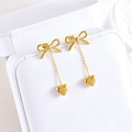 Boucles d'oreilles nœuds dorées avec longs pendentifs cœur dans une boîte à bijoux - Boucles d'oreilles