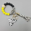 Detail of cow print silicone bead keychain with Mama charm and leather tassel decoration - Bright Yellow