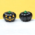 Detailed view of two small black Halloween pumpkins on a white textured plate - Solid Black