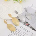 Detail of gold and silver lava texture oval drop earrings on minimalist display - Gold EH009 (Spiral Oval)