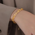 Elegantes goldenes Gliederkettenarmband mit Wellenmuster getragen zum Blazer Ärmel - Armband / Gold