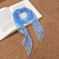 Detailed view of a vintage blue checkered printed silk scarf on an open book background - Blue Plaid