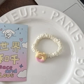 Détail d'un chouchou en satin blanc crème avec une breloque d'ours beignet mignon - Donut