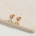 Close-up of golden fish earrings inlaid with colorful zircons on marble base - Colorful Zircon Fish