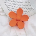 Detail shot of a matte orange flower hair claw clip on a white fabric background - Orange
