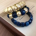 Primo piano di perle in acrilico marmorizzato e sfere dorate su vassoio per gioielli - Blu (Set da 3 pezzi)