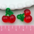 Realistic red resin cherry pendants with green leaves shown next to a pink ruler for scale - Red Acrylic Cherry (22162)