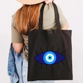 Black canvas tote bag featuring a Greek Evil Eye print carried by a model in casual wear - Design P-Layered Ring Eye-Black