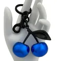 Metallic blue cherry keychain with black leaf and climbing hook shown being held - Blue Agate Blue Cherry with Black Hardware
