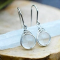 Artistic handmade wire-wrapped crystal earrings with silver spiral design on wooden base - Clear