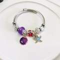 Pulsera de dijes con cuentas púrpuras, mariposa, concha y estrella de mar azul en acero inox - Morado