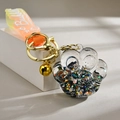 Macro detail of acrylic cat paw keychain with colorful sequins and golden bell - Quicksand Luminous Style / Black