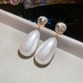 Dettaglio di orecchini con perle a goccia e borchie di cristallo rotonde in finitura oro - Bianco