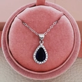 Gros plan d'un collier en zircon bleu en forme de poire dans une boîte rose - Bleu