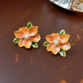 Detailed view of orange enamel flower earrings with white pearl center and green leaf accents - Silver Needle-Orange Flower Stud Earrings