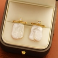 Primer plano detallado de pendientes de perlas barrocas con barras doradas y detalles de diamantes - Perla Barroca (Dorado Blanco) / Dorado con Blanco