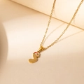 Detail of a gold Christmas necklace featuring a red enamel letter S pendant with a Santa hat - Santa Letter S