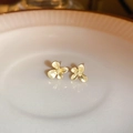 Close-up of elegant gold flower-shaped stud earrings on a minimalist white ceramic tray - Flower Stud Earrings / Gold