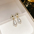 Detailed close-up of pearl flower earrings with gold plating on a textured jewelry box - Silver Pin - White Flower Pearl Drop Earrings