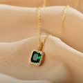 Elegant gold titanium necklace with square emerald pendant on beige silk background - Green