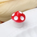 Macro view of a red resin mushroom ornament with white spots on a ceramic edge - Red