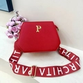 Macro shot of red textured PU leather tote bag with gold P emblem and wide strap - Red