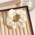 Elegant white floral lace scrunchie with pleated texture on a wooden display tray - Beige Seersucker