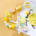 Detail of colorful beaded phone strap with star and flower charms on wooden table - M Round Tag / Yellow