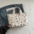 White corduroy tote bag featuring red strawberry patterns and beige ribbon handles - Off White