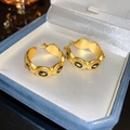 Detailed macro view of vintage gold Medusa earrings with Greek meander pattern inlay - Geometric Hoop / Gold