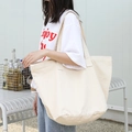 Large capacity beige canvas tote bag shown worn on shoulder for casual daily style - Off White