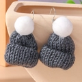Detailed macro view of dark grey knitted hat earring with white pompom texture - Gray
