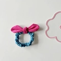 Detail view of a pink and blue suede bow hair tie on a minimalist white background - Rose Red Bow