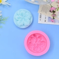 Detail of pink silicone flower mold and blue hibiscus soap creation on blue background - Red