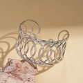 Dettaglio del bracciale rigido argento lucido con design a cerchi geometrici cavi - Argento