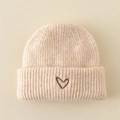 Detailed view of beige knit beanie featuring a brown heart embroidery on folded cuff - Hat / Off White
