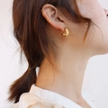 Elegant twisted gold semi-hoop earrings in 18k plated finish worn by a model - Cross Earrings Pair / Gold