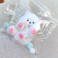 Soft white squishy cat toy with pink details in a zipper bag on plush background - Plush Bear