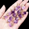 Irregular amethyst raw stone pendants with gold plated edges held in palm - Amethyst