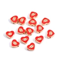 Macro shot of heart-shaped evil eye beads with red enamel and gold metal frame for DIY jewelry - Heart / Red