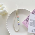 Detail of beaded phone charm with white pearls and colorful hearts on a decorative tray - Pearl Colorful Heart Bracelet