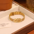 Détail d'un bracelet en maille d'acier doré avec lettre G et pendentif cœur dans un écrin à bijoux - Lettre G