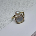 Detailed close-up of a gold ring featuring a white pearl and a cat-shaped shell design - Ring
