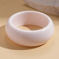 Macro detail of wide cream resin bangle on natural stone and sand background - White