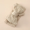 Detail of baby headband featuring large textured beige bow and soft elastic crinkle fabric - Light Coffee