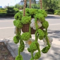 Close-up of a handmade crochet hanging plant with green leaves and small white flowers - No.4 (Brown Pot White Flower Yellow Center)