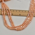 Macro-opname van 4-5 mm roze zoetwaterparels met een houten liniaal voor maataanduiding - Natuurlijk Roze - Hoge Glans
